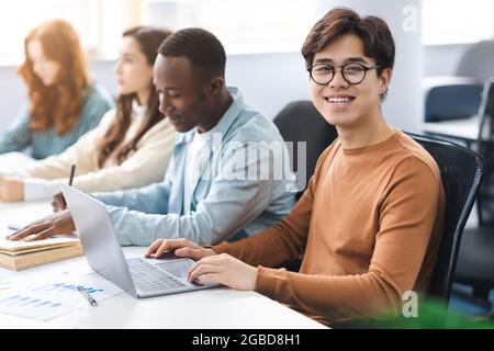 Gruppe von internationalen Personen, die Laptops in der öffentlichen Bibliothek benutzen Stockfoto