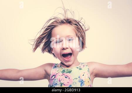 Lächelndes und fröhliches kleines Mädchen mit offenen Armen. Stockfoto