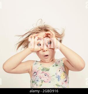 Kleines Mädchen mit den Händen über den Augen, um eine Brille zu simulieren Stockfoto