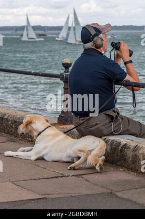 Mann mit Hund, Boote beobachten, cowes Week, Insel wight, Segelregatta, mans bester Freund, ein Mann und sein Hund. Stockfoto