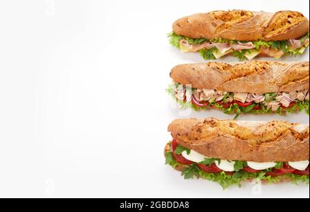 Draufsicht auf leckere verschiedene U-Boot-Sandwiches mit Fleisch und Gemüse auf weißem Hintergrund im Studio platziert Stockfoto