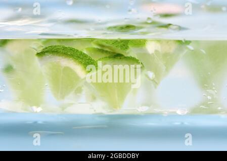 Kalkstücke schweben in einem Glas Wasser, Nahaufnahme, Hintergrund. Stockfoto