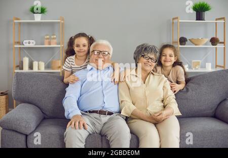 Porträt einer glücklichen Großmutter, eines Großvaters und ihrer beiden kleinen Enkelinnen. Stockfoto