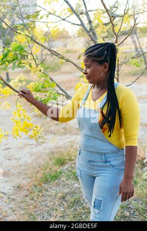 Afrikanische Frau berührt die Zweige eines Baumes Stockfoto