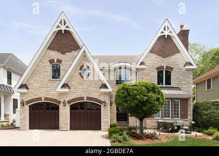 Ein komplett gemauertes Haus mit einer Garage für zwei Autos, einer Terrasse vor dem Hof, einer Ziegelsteineinfahrt und einer Mischung aus Backstein und Stein im gesamten Außenbereich. Stockfoto