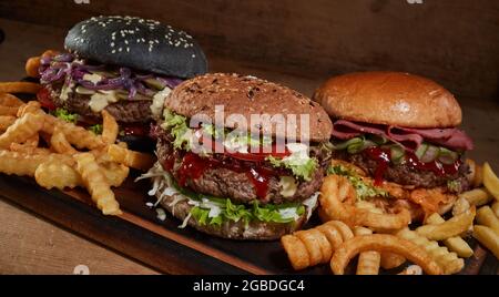 Im Studio werden leckere Burger und knusprige Pommes auf einem Holztisch serviert Stockfoto