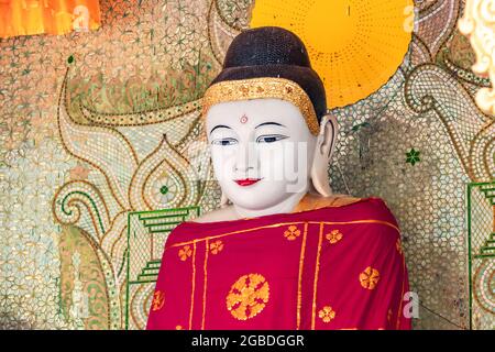 Eine verzierte Buddha-Statue mit roter Robe in einem Tempel der Shwedagon-Pagode in Burmese Yangon Stockfoto