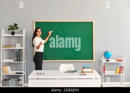 Der Lehrer schreibt eine Lektion auf der Tafel in der Schule. Stockfoto