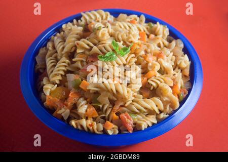 Schüssel voll mit frischen hausgemachten Makaroni-Nudeln mit Würstchen, geriebenem Käse und grünen Zwiebeln und Karotten. Stockfoto