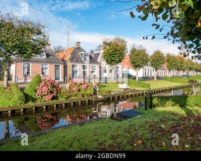 Reihe von Häusern mit Gärten am Wasser auf Eegracht Kanal in der Stadt IJlst, Friesland, Niederlande Stockfoto