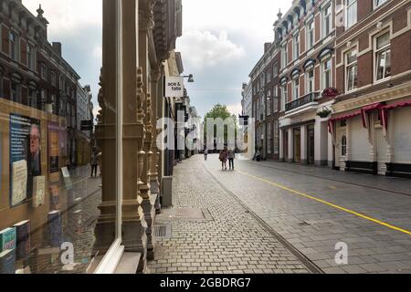 Breda, Niederlande 28. Juni 2021. Straße im Stadtzentrum mit alten historischen Gebäuden, einem Bürgersteig, Geschäften, Häusern und einem Volk, das auf einem s läuft Stockfoto