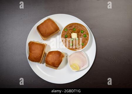 PAV Bhaji ist ein Fast-Food-Gericht aus Indien, dickes und würziges Gemüsepfarsich, gebraten und serviert mit einem weichen Brötchen/Bun Pav und Butter. Stockfoto