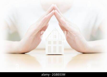 Weibliche Hände retten Miniaturhaus Stockfoto