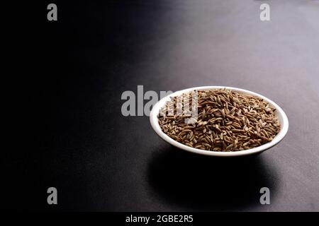 Kreuzkümmel in Schale auf schwarzem Hintergrund Stockfoto