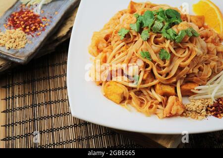 Nahaufnahme von köstlichem Thai Pad mit Garnelen und Gewürzen auf einem weißen Teller Stockfoto