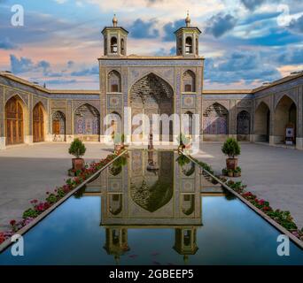 Shiraz, Iran - 2019. Mai: Iranische Frau, die bei Sonnenuntergang am Pool der Nasir al-Mulk Moschee steht. Die Nasir Al-Mulk Moschee ist auch als Rosa Moschee bekannt. Stockfoto