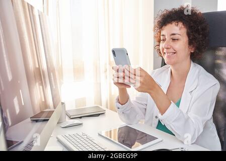 Eine Ärztin, die ihr Smartphone am Arbeitsplatz benutzt Stockfoto