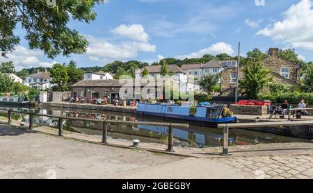 Ein Schmalschiff auf dem Leeds Liverpool Canal an der Spitze der fünf Rise Locks in Bingley, Yorkshire. Das Five Rise Locks Cafe ist im Hintergrund. Stockfoto