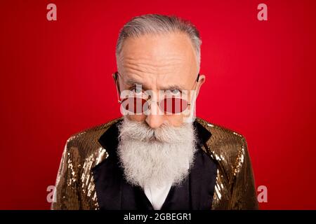 Foto von Alter schöner Mann aussehen verdächtige Brillen unglücklich tragen Blazer isoliert über roten Hintergrund Stockfoto