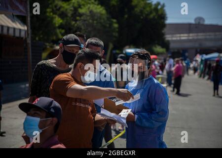 Tijuana, Mexiko. August 2021. Ein Migrant zeigt einem Gesundheitshelfer ein Stück Papier, während er am Grenzübergang El Chaparral auf eine Corona-Impfung wartet. Migranten mussten jedoch keinen Ausweis vorweisen. Die Impfkampagne wurde vom Gesundheitsministerium des mexikanischen Bundesstaates Baja California organisiert. Rund 500 Migranten, die im improvisierten Lager am Grenzübergang lebten, sollten den Corona-Impfstoff von Pfizer-BioNTech erhalten. Kredit: Stringer/dpa/Alamy Live Nachrichten Stockfoto