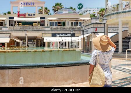 Weibliche Touristen in einem übergroßen Hut und Strandtasche mit Blick auf die geschlossenen Geschäfte, Restaurants und Veranstaltungsorte, Commercial Center Safari Las Americas Stockfoto