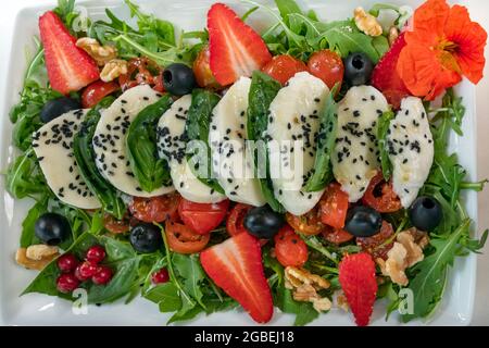 Köstlicher Caprese-Salat zum Teilen, beliebtes italienisches Gericht mit frisch geschnittenem Mozzarella-Käse, Kirschtomaten und Basilikum und anderen Zutaten Stockfoto