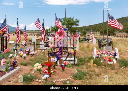 Cerro, New Mexico - EIN ländlicher Friedhof, auf dem Gräber mit Blumen und Fahnen geschmückt sind. Stockfoto