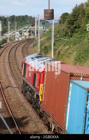 Diesel-elektrische Lokomotive der Baureihe 66, die am 3. August 2021 den Containerzug auf der West Coast Main Line in der HEST Bank, Lancashire, transportiert. Stockfoto