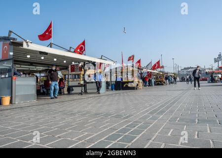 Eminonu, Istanbul, Türkei - 02.27.2021: Fast leere Bootsrestaurants mit Fischbraten auf dem Eminonu-Platz mit türkischen Flaggen Stockfoto