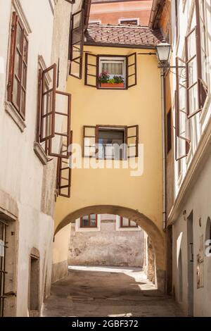 Bild einer typischen Straße aus dem Stadtzentrum von Skofja Loka, Slowenien, in der Nähe der Katstle, mit einem schmalen alten Haus über einer Straße. Skofja Loka ist eine Stadt Stockfoto