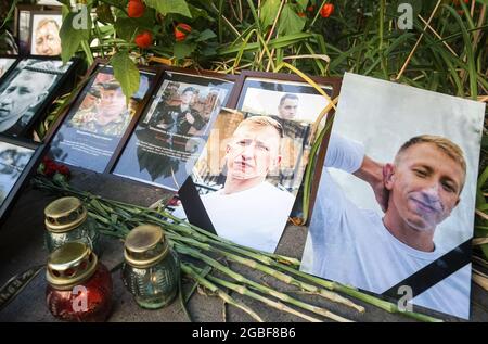 Kiew, Ukraine. August 2021. Blumen und Kerzen sind mit Fotos des belarussischen Oppositionellen und Leiters des belarussischen Hauses in der Ukraine Vitaly Schischow vor der belarussischen Botschaft während eines Protestes in seinem Gedächtnis hinterlassen. Der belarussische Aktivist Vitaly Schischow wurde tot aufgefunden, erhängt in einem Hauptpark unweit seines Hauses, angeblich von der nationalen Polizei der Ukraine. Kredit: SOPA Images Limited/Alamy Live Nachrichten Stockfoto