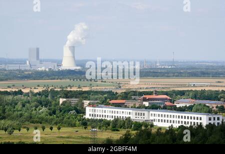 30. Juli 2021, Sachsen, Rötha/OT Mölbis: Von einem 30 Meter hohen Aussichtsturm auf dem Rundweg des ehemaligen Schutthaufens haben Besucher einen Blick auf die ehemals schmutzige und jetzt grüne Landschaft der neu besiedelten Industrie und des Kraftwerks Lippendorf (im Hintergrund). Die Sanierung des Rundweges mit Sitzmöbeln, Wegweisern und Designokaten ist eines der Projekte der Dorfentwicklungsgesellschaft, die neben der Neugestaltung des Schlossparks im Zentrum des Dorfes auch den Schutthaufen, Die von Bürgerrechtlern als Wallfahrtsort genutzt wurde i Stockfoto