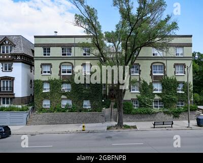 Kleines flaches Apartmentgebäude im alten Stil an einer Hauptstraße, mit Weinreben bedeckt Stockfoto