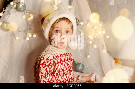 Aufgeregt Kind hält Geschenk in der Nähe weihnachtsbaum. Porträt eines glücklichen Jungen Stockfoto