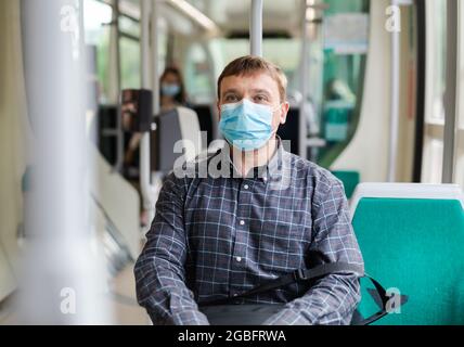 Mann in schützender medizinischer Maske fährt im öffentlichen Verkehr Stockfoto