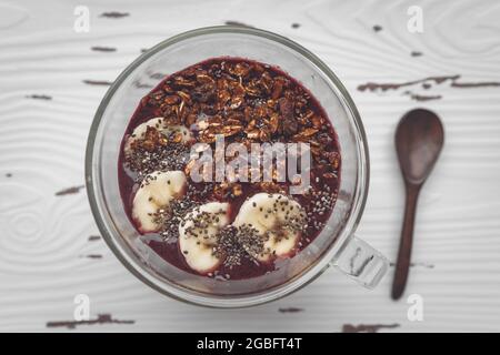 Acai Smoothie Frühstückschale mit Bananenscheiben, Chiasamen und Müslirezept. Gesunde gefrorene Snacks behandeln die Draufsicht zu Hause Stockfoto