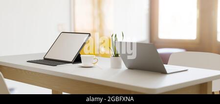 Moderner, heller Arbeitsplatz in der Campus-Bibliothek, zwei Geräte auf dem Tisch, intelligentes Tablet mit Tastatur in leerem Bildschirm-Modell, Co-Working-Bereich im Café, 3d-Renderi Stockfoto