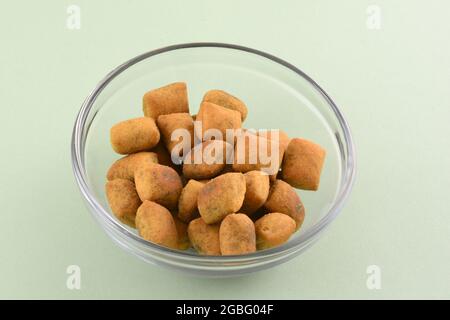 Mini-Brotscheiben mit griechischem Basilikum-Pesto-Geschmack in Glas-Snack-Schüssel auf hellgrünem Hintergrund Stockfoto