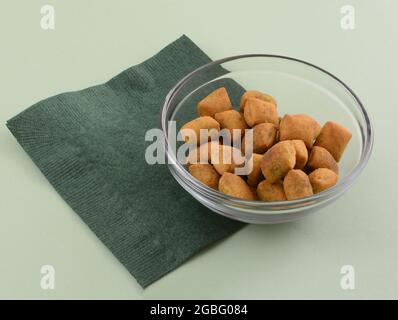 Mini-Brotsticks mit griechischem Basilikum-Pesto-Geschmack in Glas-Snack-Schale mit dunkelgrüner Serviette auf hellgrünem Hintergrund Stockfoto