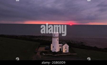 Hunstanton, Großbritannien. August 2021. Am 2. August 2021 geht die Sonne hinter dem alten Leuchtturm von Hunstanton am Ende der Tageslichtstunden in Hunstanton, Norfolk, Großbritannien, unter. Quelle: Paul Marriott/Alamy Live News Stockfoto