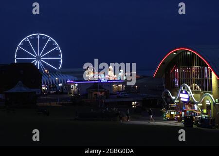 Hunstanton, Großbritannien. August 2021. Die Nachtlichter von Hunstanton vom Green aus gesehen und das View-Riesenrad, die Pier-Vergnügungen und die Messe Big Wheel und Helter Skelter, in Hunstanton, Norfolk, Großbritannien, am 2. August, 2021 Kredit: Paul Marriott/Alamy Live Nachrichten Stockfoto