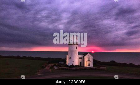 Hunstanton, Großbritannien. August 2021. Am 2. August 2021 geht die Sonne hinter dem alten Leuchtturm von Hunstanton am Ende der Tageslichtstunden in Hunstanton, Norfolk, Großbritannien, unter. Quelle: Paul Marriott/Alamy Live News Stockfoto