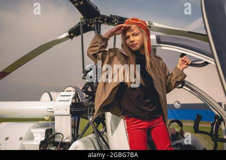 Serious preteen Mädchen in Fliegerhut in Tür von offenen Hubschrauber Stockfoto