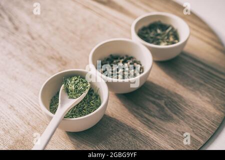 Chinesischer grüner Tee lose Blätter Verkostung Auswahl Holztablett auf dem Tisch mit drei Tassen für Getränke Verkostung. Japanischer Matcha, königsweiße Pfingstrose, Schmetterling Stockfoto
