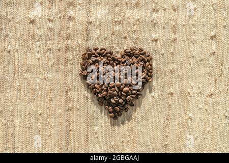 Kaffeebohnen oben flache Ansicht des herzförmigen Café Hintergrund Kaffee Liebhaber Konzept auf rustikale Tasche Textur Stockfoto