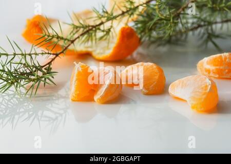Tangerine Schichten auf einer weißen Tabelle in Nahaufnahme. Saftig süße tropische Früchte für die Neujahrsferien. Das Konzept von Weihnachten, Winterstimmung. Mandarinen ein Stockfoto