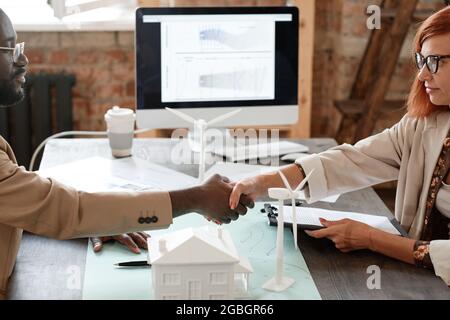 Geschäftsmann und Geschäftsfrau schüttelten sich nach Abschluss eines Deals bei der Besprechung die Hände an den Tisch Stockfoto