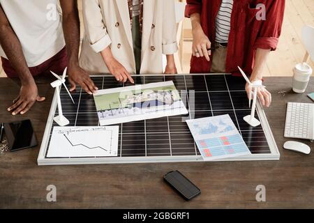 Nahaufnahme einer Gruppe von Ingenieuren, die an einem Tisch stehen und gemeinsam den Entwurf eines neuen Gebäudes studieren Stockfoto