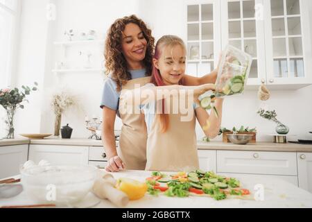 Nahaufnahme von Mutter und Tochter, die in der Küche vegane Pizza zubereiten Stockfoto
