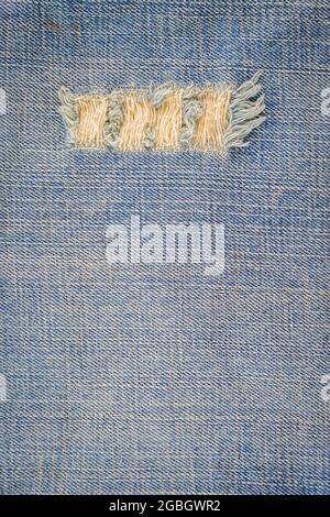 Blaue jean-Textur mit einem Loch und Fäden, die den Hintergrund zeigen Stockfoto